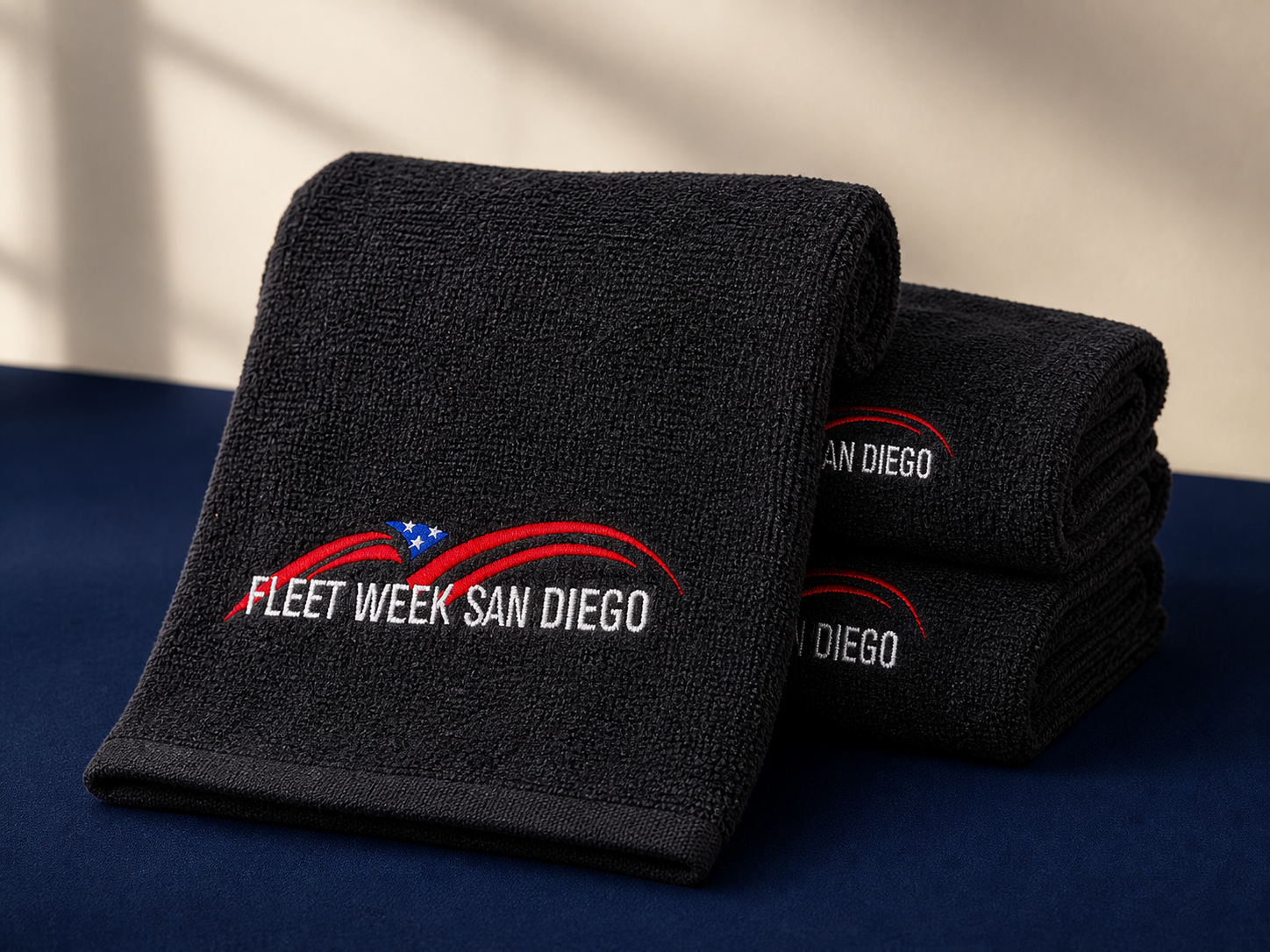 Black Fleet Week towels with detailed multicolor embroidery in a clean nautical studio setting